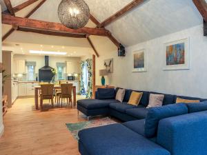 奇彭纳姆Woodmans Cottage Nables Farm的一间带蓝色沙发的客厅和一间厨房