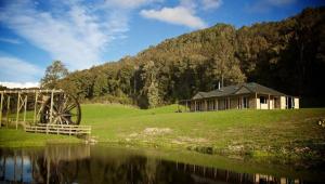 Totara FlatAhaura Lodge & Waterwheel Farm Stay的水体旁山丘上的房屋