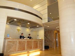 神户神户流明酒店的两个男人站在大厅的柜台上