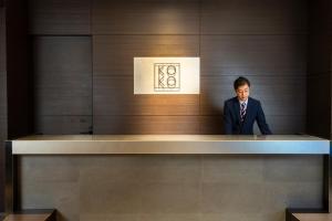 福冈KOKO HOTEL Fukuoka Tenjin的穿着西装的人站在柜台上