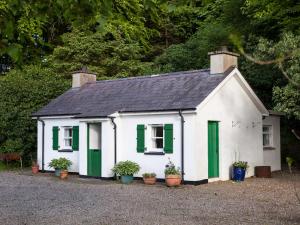 GortinMr McGregors' Cottage的一座白色的小房子,有绿色百叶窗和植物
