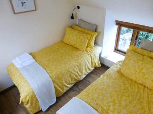 滨海韦斯顿The Old Cottage的一间卧室设有两张带黄床单的床和窗户。