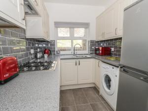康威22 Uppergate Street的厨房配有白色橱柜、洗衣机和烘干机