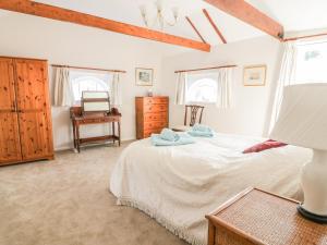 萨德伯里Stable Cottage的卧室配有一张床、一张书桌和窗户。