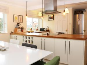 塞米斯湾Cable House的厨房配有白色橱柜和木制台面