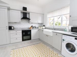 威勒尔Sunlight Soap Cottage的厨房配有白色橱柜、洗衣机和烘干机