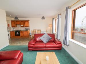 班多伦Apartment 42的客厅配有红色皮革沙发和桌子