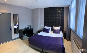 阿姆斯特丹德洛拉酒店的一间卧室配有一张带紫色床单和镜子的床