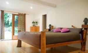 BilpinTrue North - 4BR Home & Garden in Bush Setting with Huge Bath的一间卧室配有一张带粉红色枕头的木床。