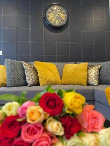 Le RaincyKEYS&HOME L’escapade Parisienne - T2 Cosy & Confort的花束在沙发上,长着钟