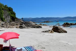 桑亨霍Hostal Casa Aurita Adults Only的沙滩上,沙滩上摆放着红色的遮阳伞和椅子