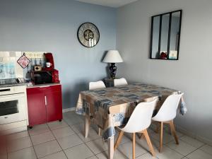 TréffiagatLa Rose des Mers的厨房配有带白色椅子的桌子和红色橱柜。
