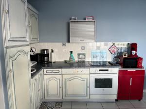 TréffiagatLa Rose des Mers的厨房配有白色橱柜和红色炉灶烤箱