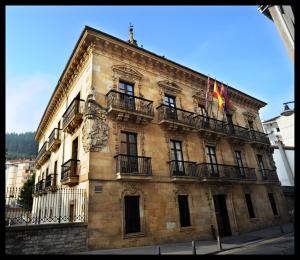 埃尔穆阿Piso reformado en el centro de Euskadi的一座大型石头建筑,设有阳台和旗帜