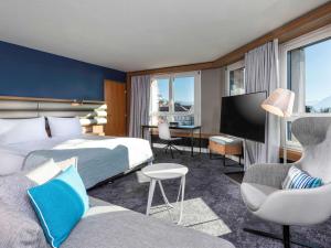 洛桑Mövenpick Hotel Lausanne的配有一张床和一张书桌的酒店客房