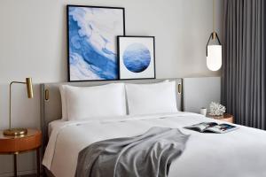 迪拜云溪港葳达酒店的卧室配有白色的床,墙上挂有两幅画作