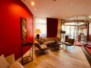 德累斯顿德累斯顿市多美洛酒店的客厅设有红色的墙壁、沙发和椅子