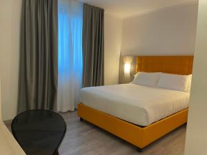 皮亚韦河畔诺文塔奥姆尼亚酒店的酒店客房配有一张床铺和一张桌子。