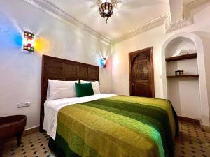 丹吉尔Kasba blanca的一间卧室配有一张带绿色和黄色毯子的床
