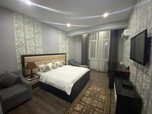 杜尚别Sunrise Apartments的一间卧室配有一张床、一台电视和一张沙发