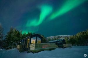 阿尔塔Flatmoen Natur Lodge的雪中极光下的小屋