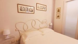 比萨Relais Pacinotti Rooms的白色卧室配有白色的床和墙上的两张照片