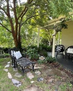 MylorFleetwood Cottage Bed and Breakfast的庭院设有两把椅子和一张长凳。