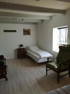 瓦埃勒Bøgehus的卧室配有床、椅子和窗户。