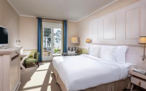 巴特萨罗皮斯库夫Precise Resort Bad Saarow - Golf & Spa的酒店客房设有一张白色大床和一张书桌