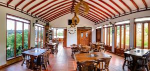 莱瓦镇Hotel Campestre Cordillera de los Andes的餐厅设有木桌、椅子和窗户。