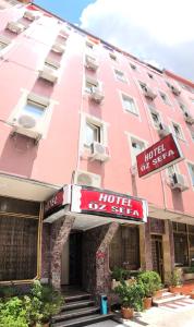 伊斯坦布尔HOTEL ÖZSEFA的粉红色的建筑,前面有酒店标志