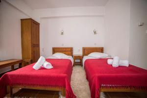 内莱多科利Ξενώνας Πατρικό的一间设有两张带红色床单和白色毛巾的床的客房