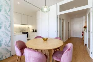 维亚纳堡Santa Luzia Views - Modern City Centre Apartment with Iconic Views的厨房以及带木桌和粉红色椅子的用餐室。