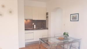 扎达尔Apartmani Milin的厨房配有白色橱柜和玻璃桌