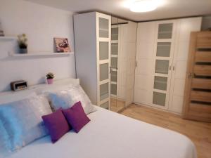 马里扬泊列Marijampolės jaukūs apartamentai的卧室配有白色床和紫色枕头