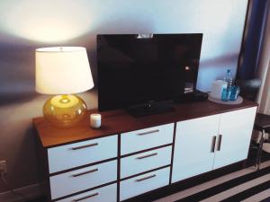 蒙托克蒙托克蓝色酒店的白色橱柜顶部的电视机,配有台灯