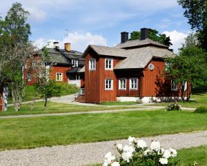 SöderbärkeHandlarens villa - Vandrarhem de luxe的大型木制房屋设有白色窗户和庭院