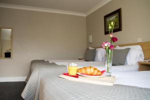 班克拉那海港酒店 的一张带一盘面包和一杯橙汁的床