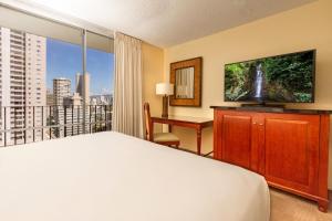 檀香山Ohia Waikiki Studio Suites的一间卧室配有一张床、一张书桌和一个大窗户