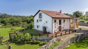 利亚内斯Casa Rural Llanes Asturias的山丘上带围栏的房子