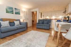 韦德布里奇Harbour House Apartment的一间带蓝色沙发的客厅和一间厨房