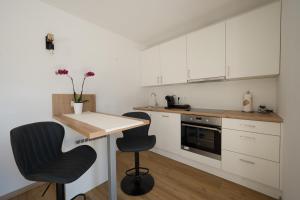 巴德哥依斯恩Austrian Apartments的厨房配有白色橱柜、桌子和两把椅子