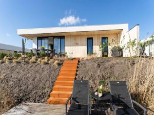 泽沃德Family villa with garden and jetty的山丘上的房子,配有两把椅子和一张桌子