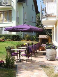 塞巴特阿尔贝克德利亚维尔旅馆的一个带桌椅和紫色雨伞的庭院