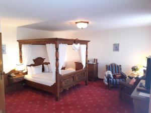 巴登-巴登埃尔哈妮酒店的一间卧室配有一张天蓬床和一把椅子