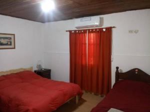 圣达菲Casa-quinta Colastine Norte, Santa fe Argentina的一间卧室配有床和红色窗帘