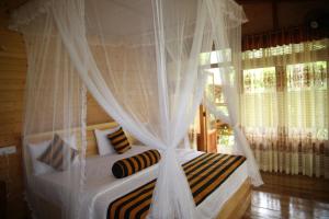 埃拉Eco Village的卧室配有带白色窗帘的天蓬床
