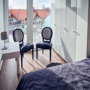巴拉通雷勒Lelle Marine Resort Voila Apartman的一间卧室配有两把椅子、一张桌子和一个窗户。