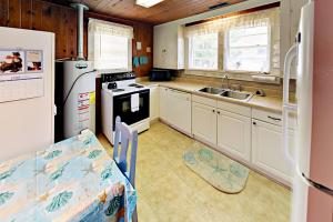 默特尔比奇Vintage Bungalow的厨房配有白色橱柜、水槽和冰箱。