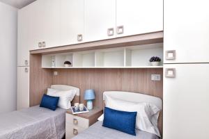 圣特奥多罗Residence Chiaro di Luna的小客房内的两张床,配有蓝色枕头